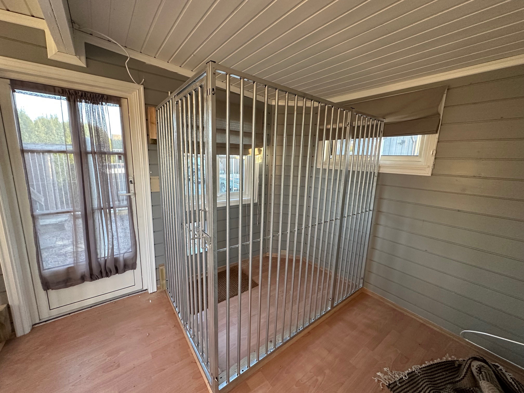 Femunden Spil hundegård montert innendørs med lyse loddrette spiler